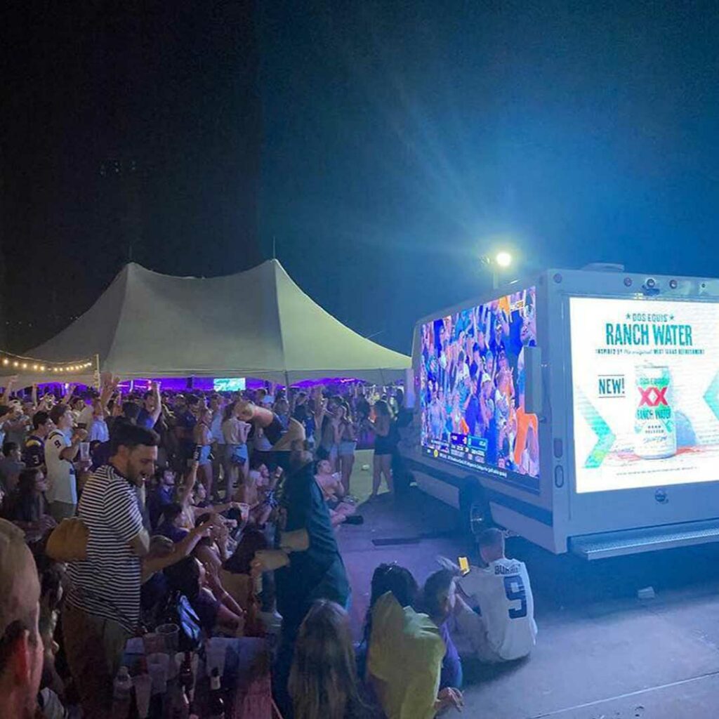 The BrandVan livestreaming a sports game at an outdoor bar, while advertising for clients on the back screen.